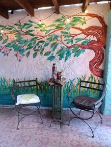two chairs and a table in front of a wall with a painting at Patio Urbano Suites & beds in Montevideo