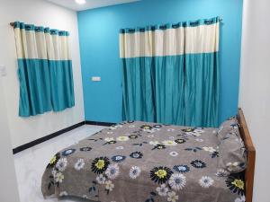 a bedroom with a bed with blue walls and blue curtains at Maatrukul Homestay in Revadanda