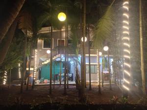 a building with palm trees in front of it at night at Maatrukul Homestay in Revadanda