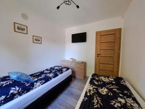 a bedroom with two beds and a wooden door at Domki Kajuta 3 in Żarnowska