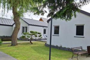 a white house with a bench and a tree at Domki Kajuta 3 in Żarnowska