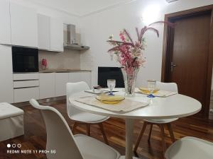 a white dining room table with chairs and a vase of flowers at Principe Michelangelo in Bari