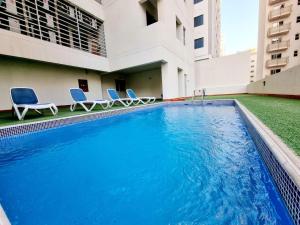 a swimming pool with two chairs and a building at Aspire Tower # Two Bedroom Luxury Suite Juffair in Manama
