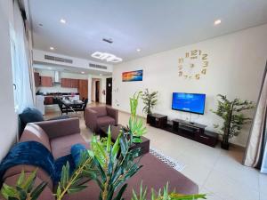a living room with a couch and a flat screen tv at Aspire Tower - Two Bedroom Sunny Staycation in Manama