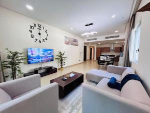 a living room with two couches and a clock on the wall at Aspire Tower - Breezy Two Bedroom in Juffair in Manama