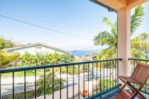 a balcony with a chair and a view of the ocean at Palm Tree House by Homie in Ponta Delgada