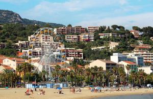 a beach with a ferris wheel and people on the beach w obiekcie SELECT'soHOME - Studio au cœur du centre-ville du Lavandou à quelques pas de la plage ! - Services hôteliers - AREV w mieście Le Lavandou
