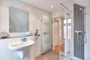 une salle de bain blanche avec lavabo et douche dans l'établissement "Klein-Wiebke" in der Villa Wilhelmine, à Borkum