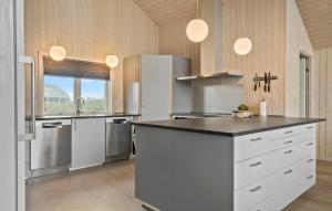 a large kitchen with white appliances and a counter top at Cozy Home In Harboøre With Kitchen in Langerhuse