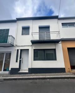 a white building with a balcony on a street at Vagabond Mermaid Guesthouse in Ponta Delgada