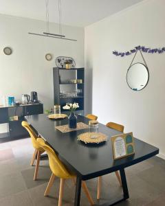 a dining room with a black table and yellow chairs at Vagabond Mermaid Guesthouse in Ponta Delgada