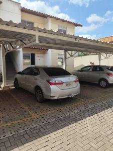 two cars parked in a parking lot in front of a house at Divino Apartamento Sete lagoas in Sete Lagoas