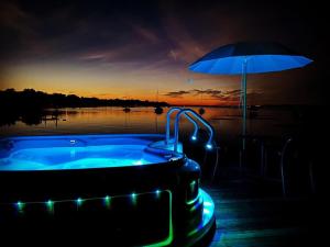 a hot tub with an umbrella next to a body of water at Strandhotel SüdSee Diessen am Ammersee in Dießen am Ammersee