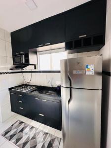 a kitchen with a stainless steel refrigerator and black cabinets at AP Massangano in Petrolina