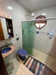 a bathroom with a shower and a blue toilet at Recanto dos Cajueiros in Cabo Frio +3 photos
