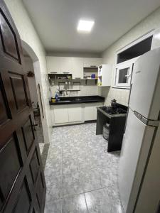 a kitchen with white cabinets and a refrigerator at Recanto dos Cajueiros in Cabo Frio
