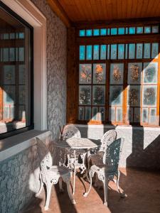 a table and chairs in a room with windows at Divine moments apartment@Calbucet ski slope in Predeal