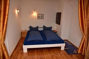 a bedroom with a bed with blue sheets and wooden floors at Ferienwohnung am Hafen in Lübbenau