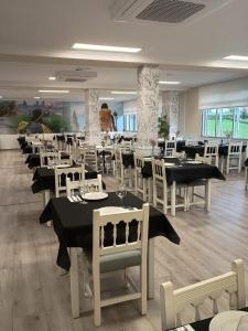 a dining room with tables and white chairs at Pensión A Codeseira Melide in Melide