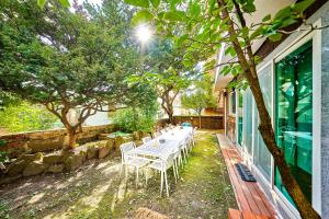 - une table avec des chaises blanches sur la terrasse dans l'établissement Jt Tailored Service Home Near Hyehwa Station, à Séoul