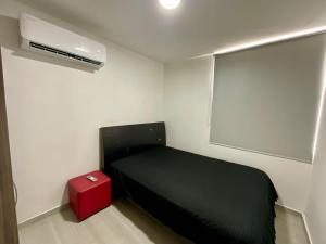 a small bedroom with a black bed and a red box at Hermoso Apto en Zona Norte Baq in La Mina