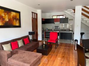 a living room with a brown couch and red chairs at Hahn des Felsens in Oxapampa