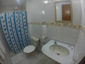 a bathroom with a sink and a toilet and a mirror at Ayruma Guest House in Cabo Frio