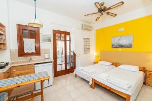 a bedroom with two beds and a kitchen with yellow walls at Aegina Town Cozy Escape in Aegina Town