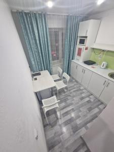 a kitchen with white cabinets and a table and chairs at 1-комнатная квартир в центре города Strekoza in Petropavlovsk