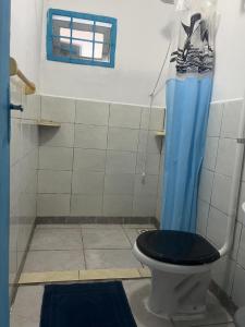 een badkamer met een toilet en een blauw douchegordijn bij casa de praia em Itapoá SC a uma quadra da praia in Itapoa
