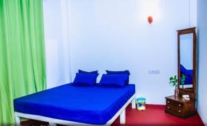 een slaapkamer met een blauw bed en een spiegel bij Dhanashi Villa Talalla in Talalla South