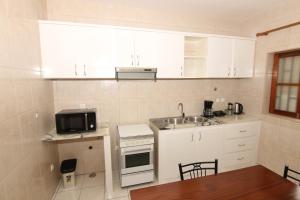 a kitchen with white cabinets and a sink and a microwave at Kasa Tabuga in Porto Novo