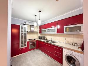 una cucina con armadi rossi e una lavatrice di Cozy Apartment Near the Pyramid, Tirana Center a Tirana
