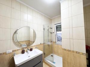 un bagno con lavandino, doccia e specchio di Cozy Apartment Near the Pyramid, Tirana Center a Tirana Altre 20 foto