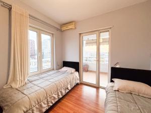 una camera da letto con due letti e una grande finestra di Cozy Apartment Near the Pyramid, Tirana Center a Tirana
