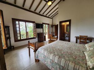 ein Schlafzimmer mit einem Bett in einem Zimmer mit Fenstern in der Unterkunft Bangalô com vista e piscina natural em Flechas in Ilhabela