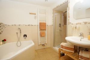 a bathroom with a bath tub and a sink at Sotterhof - Chiemgau Karte in Inzell +19 photos