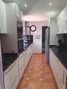 a kitchen with white cabinets and a clock on the wall at Villa happy Place in Villaverde