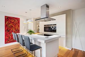 a kitchen with a large white island with chairs at EDLER WOHNRAUM Schwanenteich-Suite mit Balkon, Kaffeevollautomat, Lift & Parkplatz in Zwickau