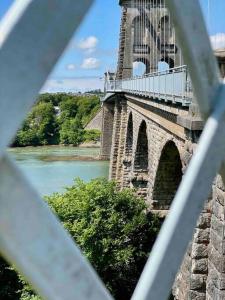 a bridge over a river with a view of it at Cosy one bed cottage in Anglesey in Llanddyfnan