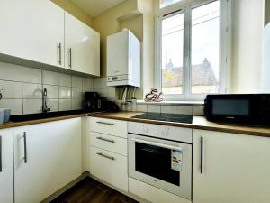 a kitchen with white cabinets and a sink and a microwave at Le Saint - By 69ALSACELO- 3 Chambres Séparées - Idéal Pro & Famille - Patio Privé - Proche Centre Ville - Smart TV - WiFi Fibre - Check-in Autonome - Parking Facile & Gratuit in Sens