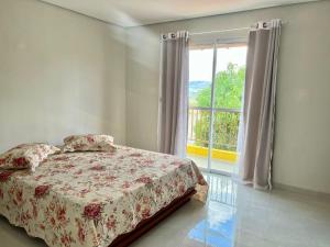 Un dormitorio con una cama y una ventana grande. en Chácara Aconchego da Serra, en Serra Negra