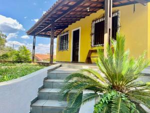 una casa amarilla con escaleras delante en Chácara Aconchego da Serra, en Serra Negra