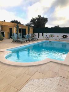 a large swimming pool with chairs around it at Villa Vona - private pool, beautiful garden in 3 BDR villa in Óbidos