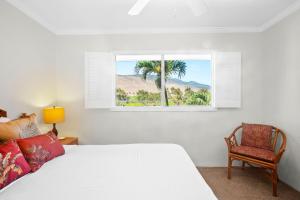 a bedroom with a bed and a window and a chair at Maalaea Kai 311 - Direct Ocean Front, Split AC in Wailuku