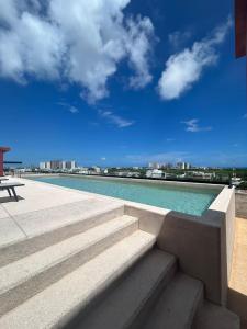 カンクンにあるNew Centric 1BR apartment with gym & poolの市街の景色を望むスイミングプール(階段付)