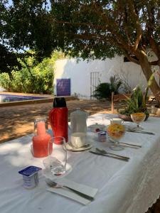 een tafel met een witte tafeldoek met een fles en glazen bij Suíte Pitangueira - Hospedaria Sonho De Infância in Mato Verde