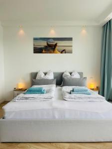 a white bedroom with two beds with blue pillows at Schleibude in Schleswig
