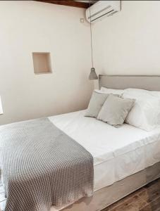 a bed with white sheets and pillows in a room at mangata suite home private pool in Spartokhórion