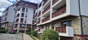 an apartment building with a car parked next to it at Free SPA Pirin lodge cosy apartment in Bansko